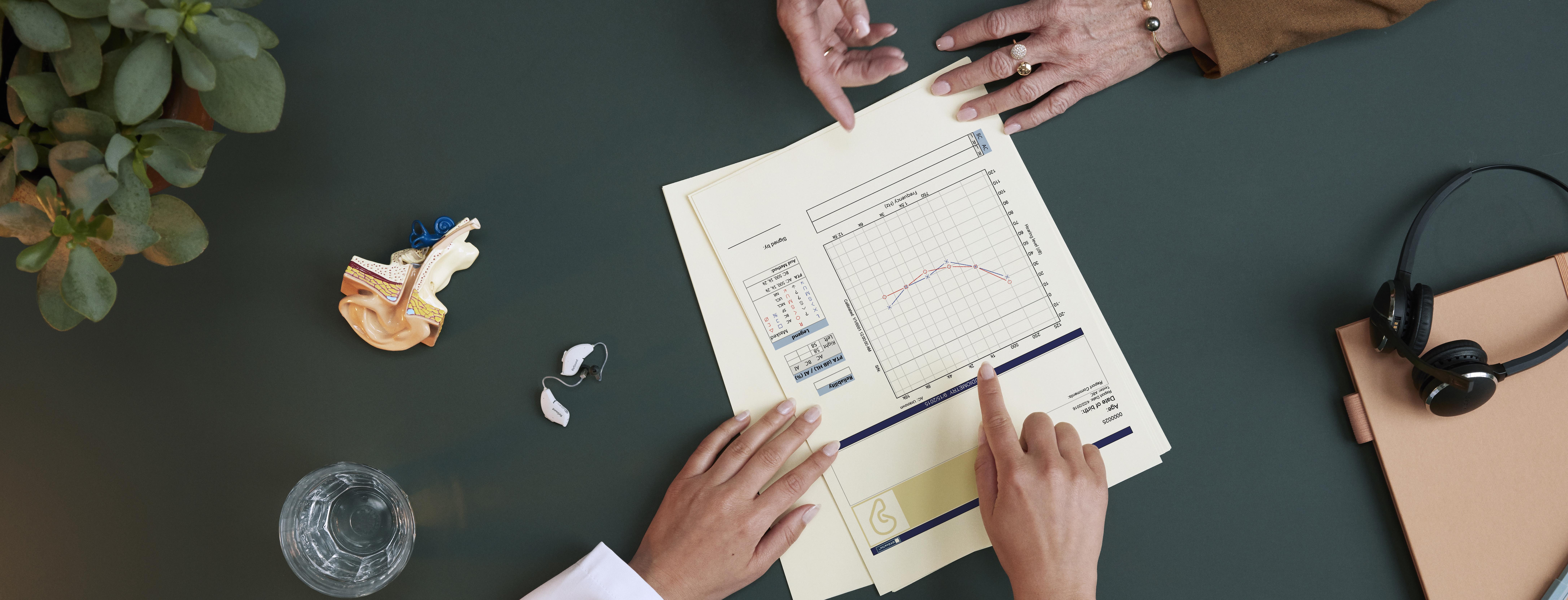 Hearing care professional advising a patient and showing an audiogram
