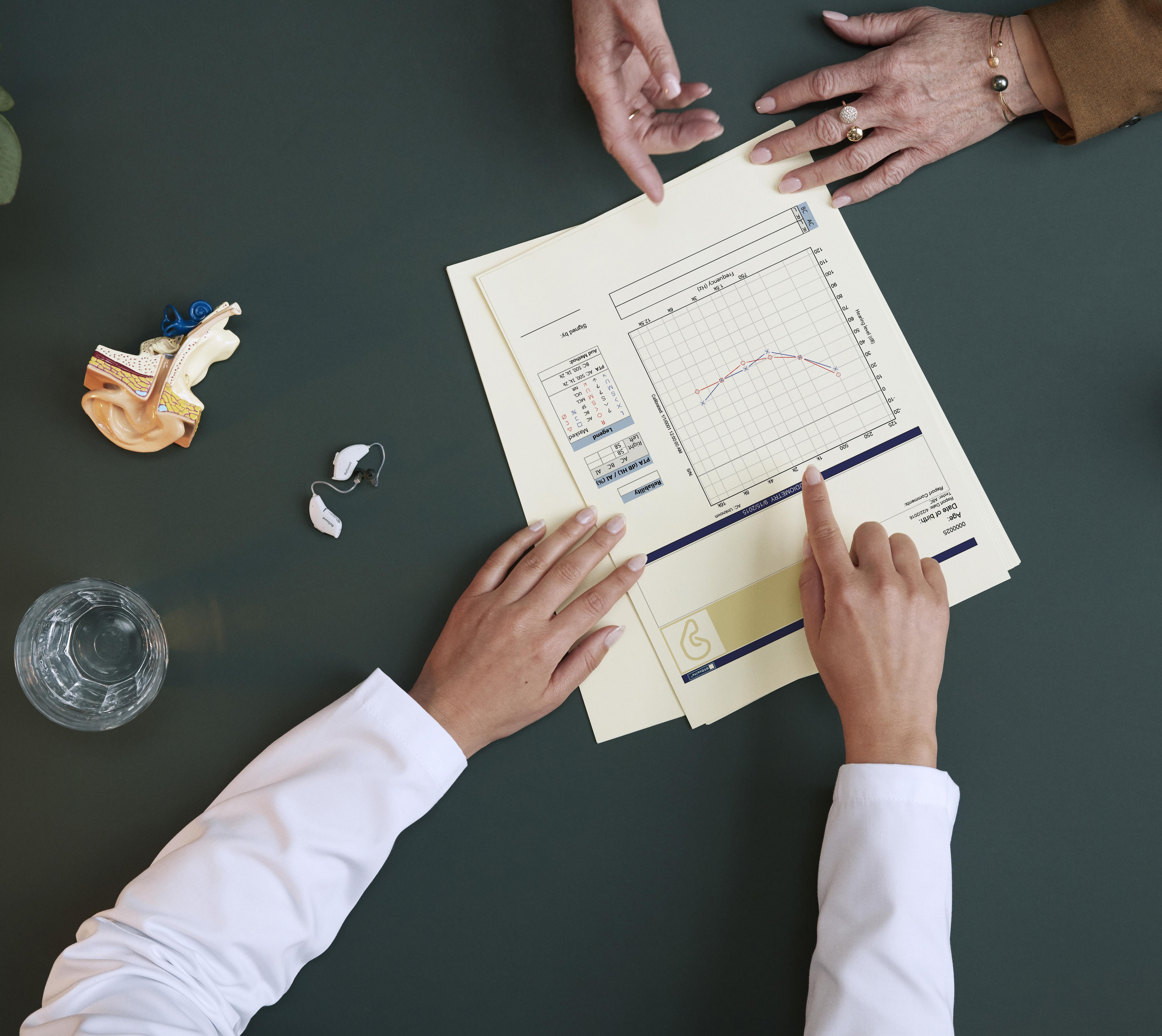 اختصاصي عناية بالسمع يقدم المشورة لمريض ويريه مخططاً للسمع.