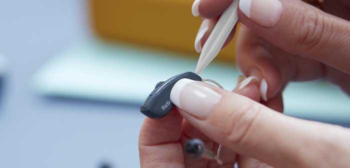 Donna che ripara un apparecchio acustico ReSound.