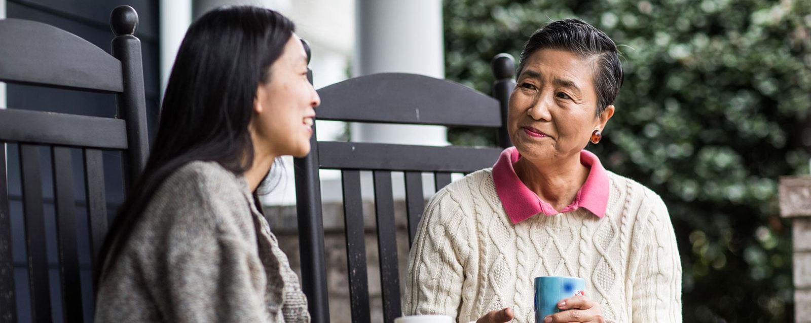 Adult woman talking on front porch with senior mother, a ReSound Key user