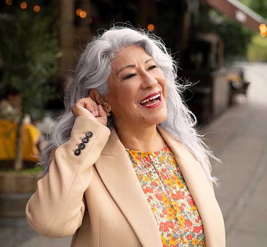 Leende kvinna som trycker på knappen på hörapparaten