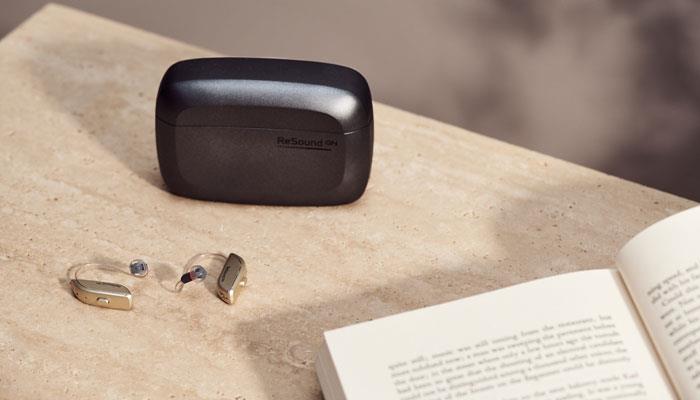 Bahnbrechende ReSound ONE RIE-Hörsysteme und Ladeschale auf einem Tisch