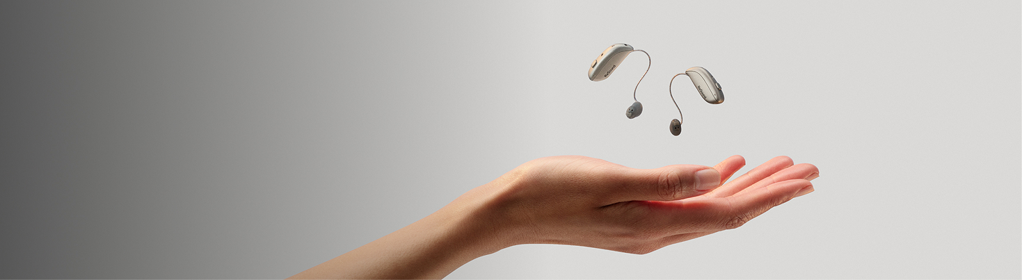 ReSound Sensia hearing aids hovering above an open palm